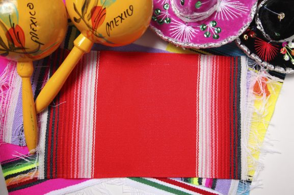 Rote Tischdecke mit bunten Maracas, Sombreros und dekorativen Elementen.