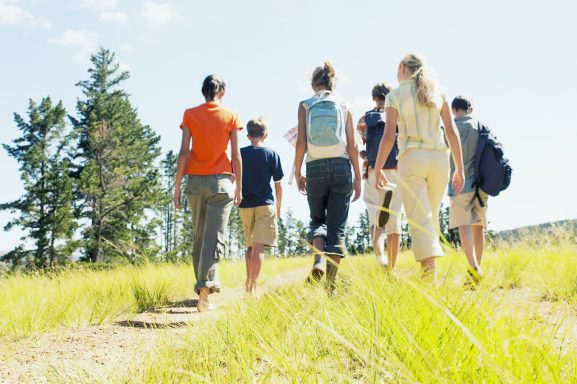 Gruppe von Menschen, die auf einem Wanderweg durch die Natur gehen.