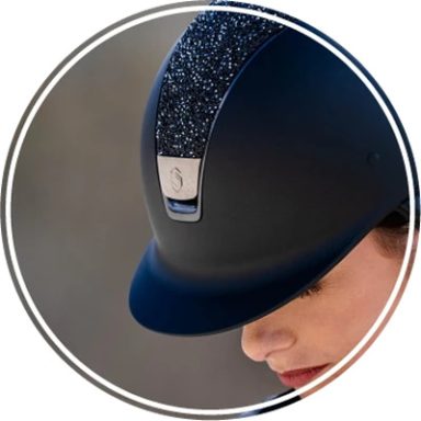 Reiterhelm in Schwarz mit glitzerndem Akzent, Trägerin schaut nach unten.
