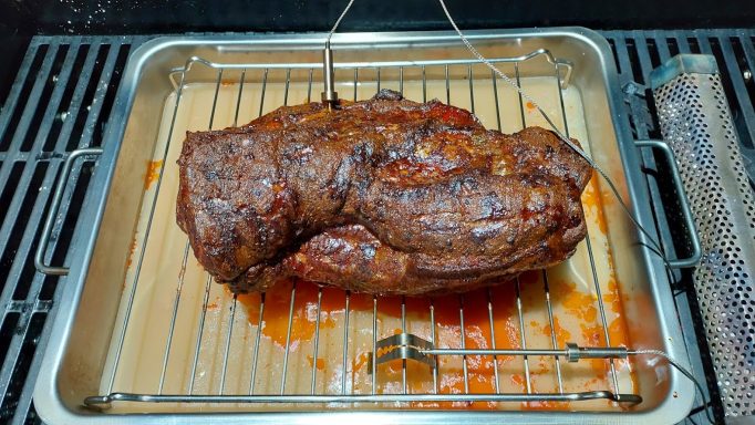 Saftiger, gegrillter Braten auf einem Rost mit Grilltropfen.