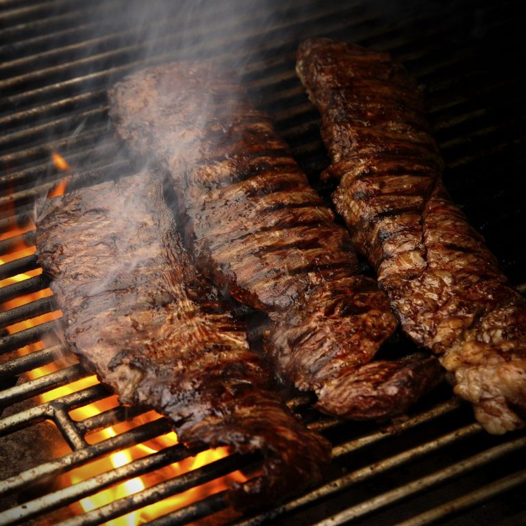 Gegrilltes Fleisch auf dem Grill, dampfend und braun.