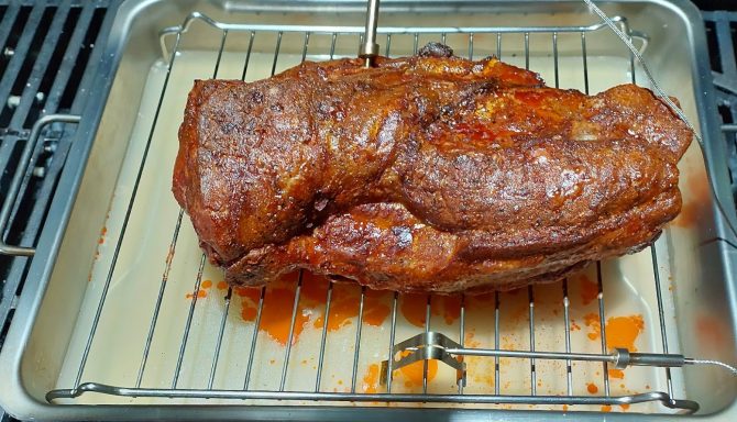 Saftiger Braten auf einem Rost in einer Backform, leicht angebräunt und glasiert.