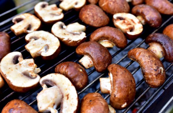 Gegrillte Champignons in Reihen auf einem Grillrost.