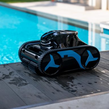 Ein schwarzer und blauer Poolroboter steht am Beckenrand.