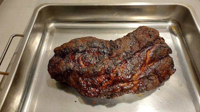 Räucherfleisch auf einer Metallplatte, dunkelbraun und leicht glänzend.