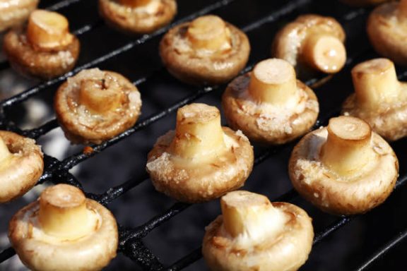 Gegrillte Champignons auf einem Grillrost.